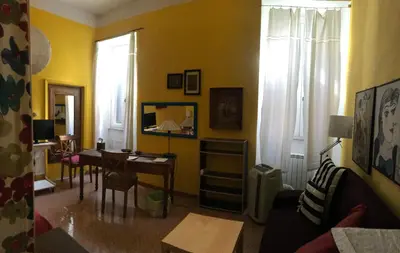 a living room with yellow walls and a table and chairs at Appartamento del Boschetto in Rome