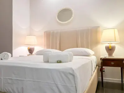 a white bed with two lamps and a mirror at Beautiful apartment within walking distance of the Vatican in Rome