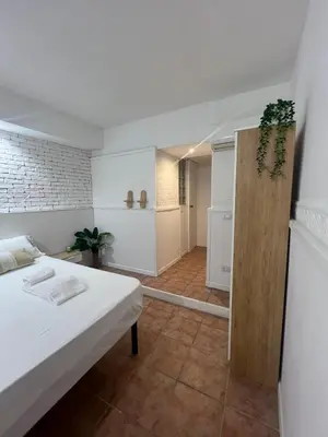 a white room with a bed and a kitchen at Cupola Rooms Vicino al Vaticano in Rome