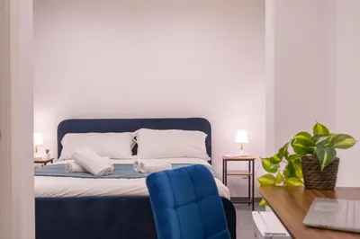 a bedroom with a bed with a blue chair and a desk at Pallaro 6 room in Rome