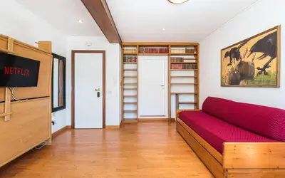 a living room with a red couch and book shelves at Vatican-Metro A Panoramic Penthouse with Jacuzzi in Rome