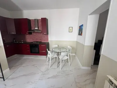 a kitchen with a glass table and white chairs at Vacanze Romane in Rome