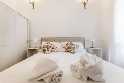 a white bedroom with a white bed with towels on it at Elegant 3-bedroom apartment near the Metro in Rome