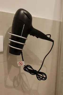 a black hair dryer with a cord plugged into it at La Casa del Viaggiatore in Rome