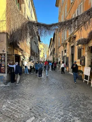 a group of people walking down a cobblestone street at Home Delfini in Trastevere in Rome