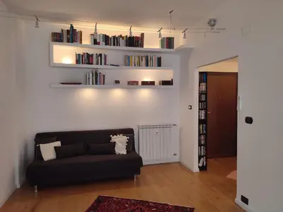 a living room with a black couch and books at Tanner's Apartment - Piramide in Rome