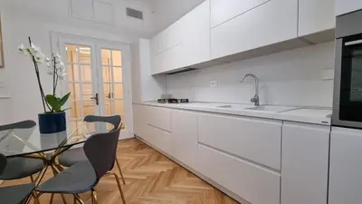 a white kitchen with a glass table and chairs at Beautiful Apartment San Pietro in Rome