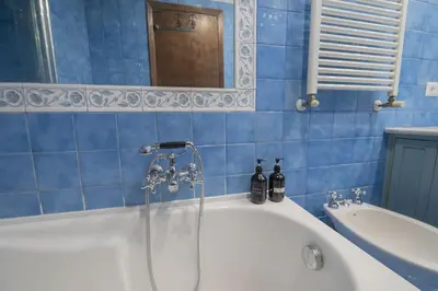 a blue tiled bathroom with a tub and a mirror at Trastevere Charming Apartment in Rome