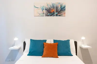 a white bed with blue and orange pillows on it at Imperial House - 300m to Metro B, Open view, 4-6pax in Rome