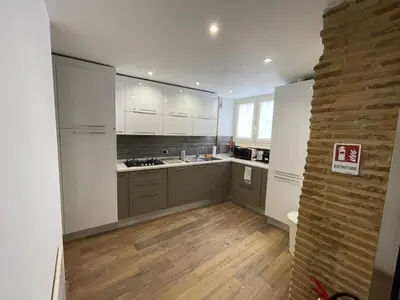 a kitchen with white cabinets and a wooden floor at Foro Romano Apartments D in Rome