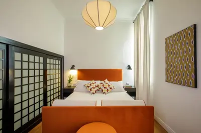 a bedroom with a large bed with a orange chair at Daplace - Serenella Apartment in Rome