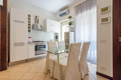 a kitchen with a glass table and white chairs at Domus Romana Trieste in Rome