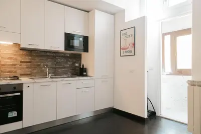 a kitchen with white cabinets and a brick wall at Domus Aura in Rome