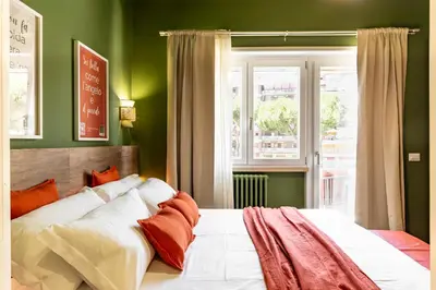 a bedroom with a bed with green walls and a window at Notte Ai Colli - Rooms & Kitchen in Rome