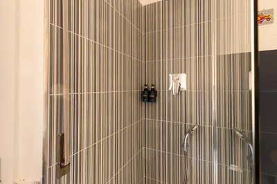 a bathroom with a shower with striped tiles at Cappuccino Pop, Apartment Metro A in Rome