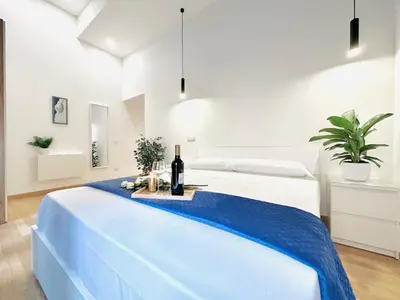 a white room with a bed with a bottle of wine at San Giovanni Lulus Home in Rome