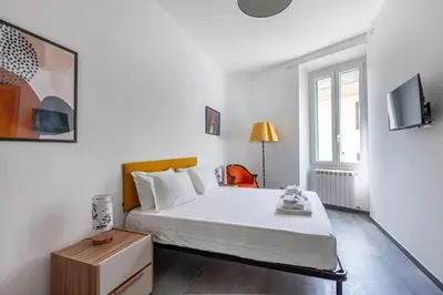 a white bedroom with a bed and a table at Ponte Milvio 3 Bedroom Apartment in Rome