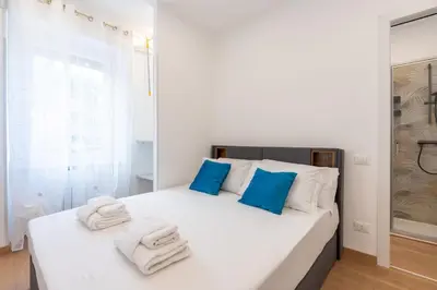 a bedroom with a white bed with blue pillows at Ponte Milvio-Olympic Stadium Modern Apartment in Rome