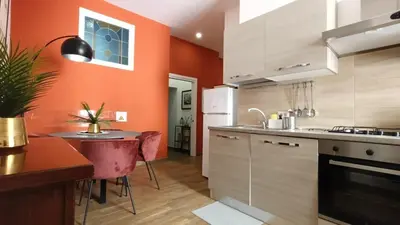 a kitchen with orange walls and a table and a counter at Laterano 190 apt at Colosseo in Rome