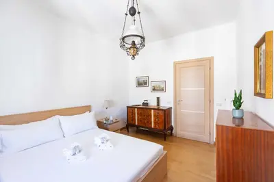 a bedroom with a white bed and a wooden dresser at Casa Arezzo - silenzioso trilocale con terrazzino privato - Cale 06 in Rome
