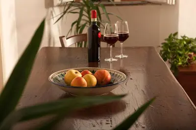 a bowl of fruit on a table with two glasses of wine at Finestre sul Tevere in Rome