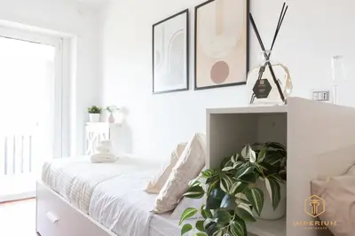 a white bedroom with a bed and a plant at Imperium Trastevere Flat - 4-6 pax, A-C, Panoramic view, 2 Baths in Rome