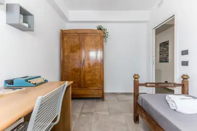 a bedroom with a desk and a bed and a wooden cabinet at L'elegante Casa Di Anna - Roma EUR in Rome