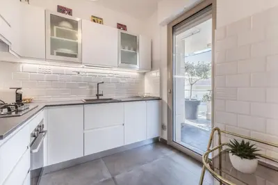 a kitchen with white cabinets and a sliding glass door at L'elegante Casa Di Anna - Roma EUR in Rome