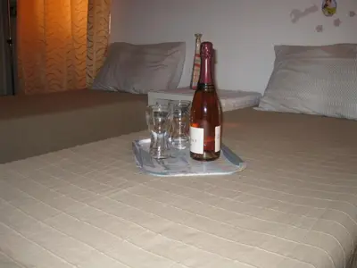 a bottle of wine sitting on a bed with glasses at Musa Apartments in Rome