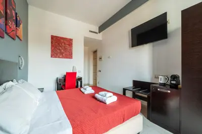 a bedroom with a bed with a red blanket and a desk at San Marco City View Rooms in Rome