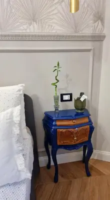 a blue nightstand with a plant on it next to a bed at LeChiaviDiCasa - Via Camilla in Rome