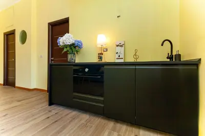 a kitchen with a black counter with a vase of flowers at Volpetti Experience-Suite in Vatican City in Rome