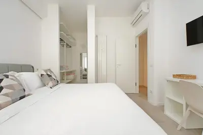 a white bedroom with a bed and a couch at Brand New Modern Apt 2 Stops to Colosseum in Rome
