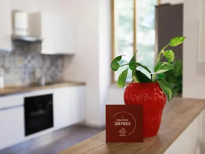 a red vase sitting on a counter with a plant in it at Enjoy Rome San Paolo Retreat in Rome