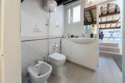 a white bathroom with a toilet and a sink at Renovated Luxury Sweet Penthouse - Campo Dei Fiori in Rome