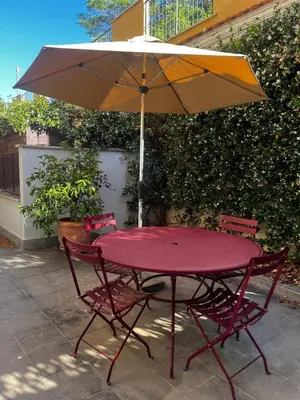 a red table with two chairs and an umbrella at Casa Jacomini in Rome