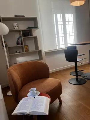 a living room with a chair with a book and a cup of coffee at Casa Jacomini in Rome
