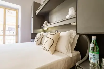 a bedroom with a bed with white pillows and a bottle at Cunabu Calatafimi in Rome