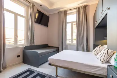 a bedroom with a bed and a couch and windows at Cunabu Castro Pretorio in Rome