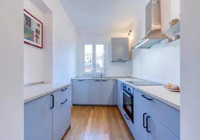 a white kitchen with white cabinets and a wooden floor at Vittoriano Pantheon apartment in Rome