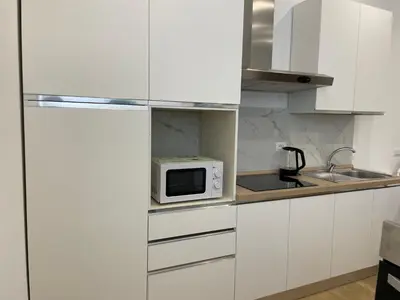 a kitchen with white cabinets and a microwave at Family Domus Via Latina in Rome