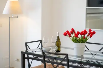 a glass table with red tulips and a bottle of wine at Pgrhome Civinini in Rome