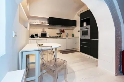 a kitchen with white cabinets and a table with a chair at Roma Suite Piazza Navona in Rome