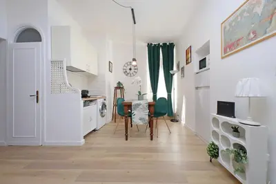 a kitchen and dining room with a table and green chairs at Domus al Colosseo by Luxury Getaways in Rome