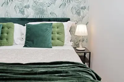 a bed with green pillows and a table with a lamp at Domus al Colosseo by Luxury Getaways in Rome