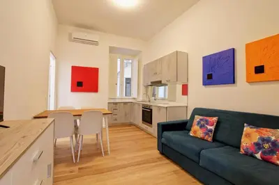 a living room with a blue couch and a kitchen at Poliziano Boutique Apartment in Rome