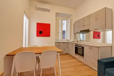 a kitchen with a wooden table and white chairs at Poliziano Boutique Apartment in Rome