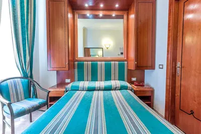 a bedroom with a bed and a mirror and a chair at Raeli Hotel Lazio in Rome