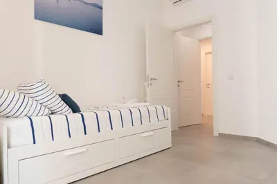a white bedroom with a bed with striped pillows at Casa Buon Vento - relax a Villa Ada in Rome