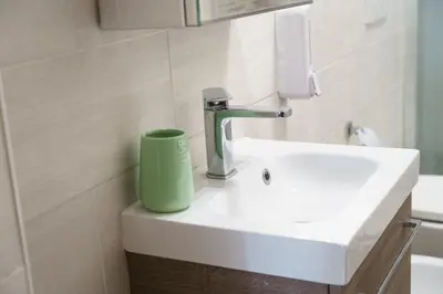 a bathroom sink with a green cup sitting on it at Apartment16 in Rome